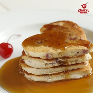 Stack of three heart shaped cherry pancakes drizzled in syrup